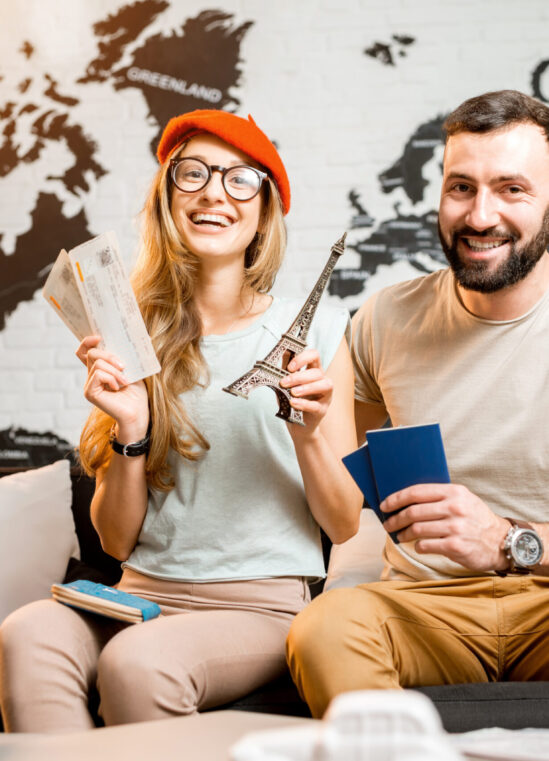 Young couple sitting with eiffel tower at the travel agency office on the world map background prepairing for a trip to Paris