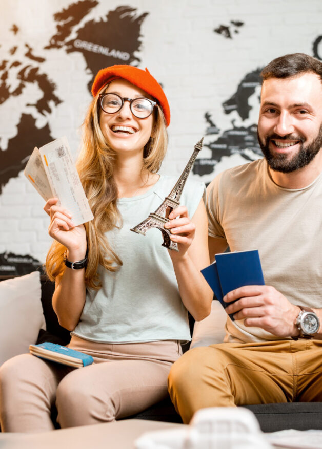 Young couple sitting with eiffel tower at the travel agency office on the world map background prepairing for a trip to Paris