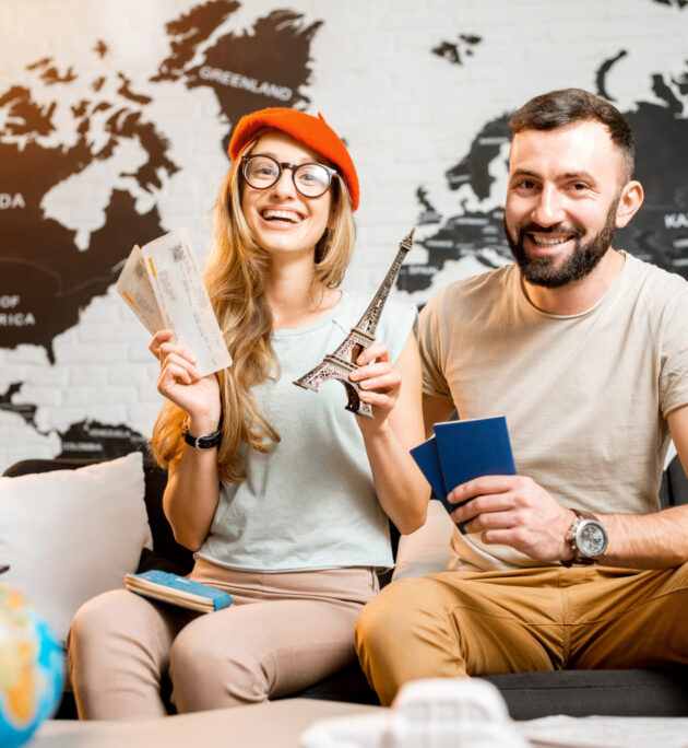 Young couple sitting with eiffel tower at the travel agency office on the world map background prepairing for a trip to Paris