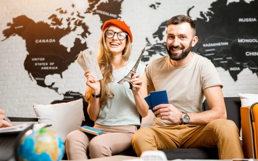 Young couple sitting with eiffel tower at the travel agency office on the world map background prepairing for a trip to Paris